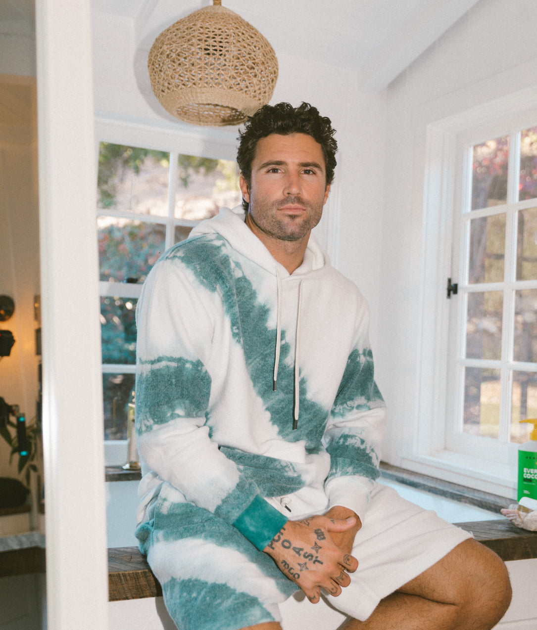 Brody Jenner seated wearing the Brody Jenner BlanketBlend Hoodie and Shorts